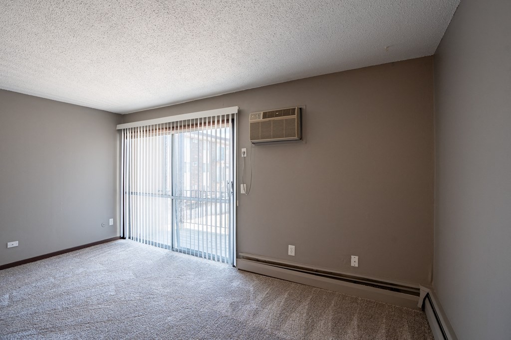 an empty living room with a sliding glass door to a balcony. Roseville, MN Rosedale Estates Apartments