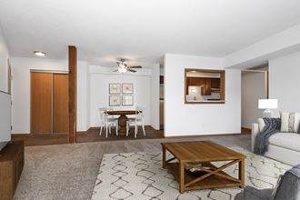 a living room in st louis park at the courtyard apartments with a couch, coffee table, and dining area in the background. - Photo Gallery 2