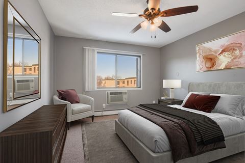 bedroom in Edge of Uptown, a residential complex in St. Louis Park. The room features a comfortable bed with neatly arranged bedding and a soothing color palette. Soft lighting creates a warm and inviting ambiance, while a window brings in natural light