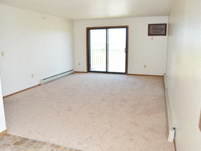 a living room with a glass sliding door. Dilworth, MN Fieldstone Apartments