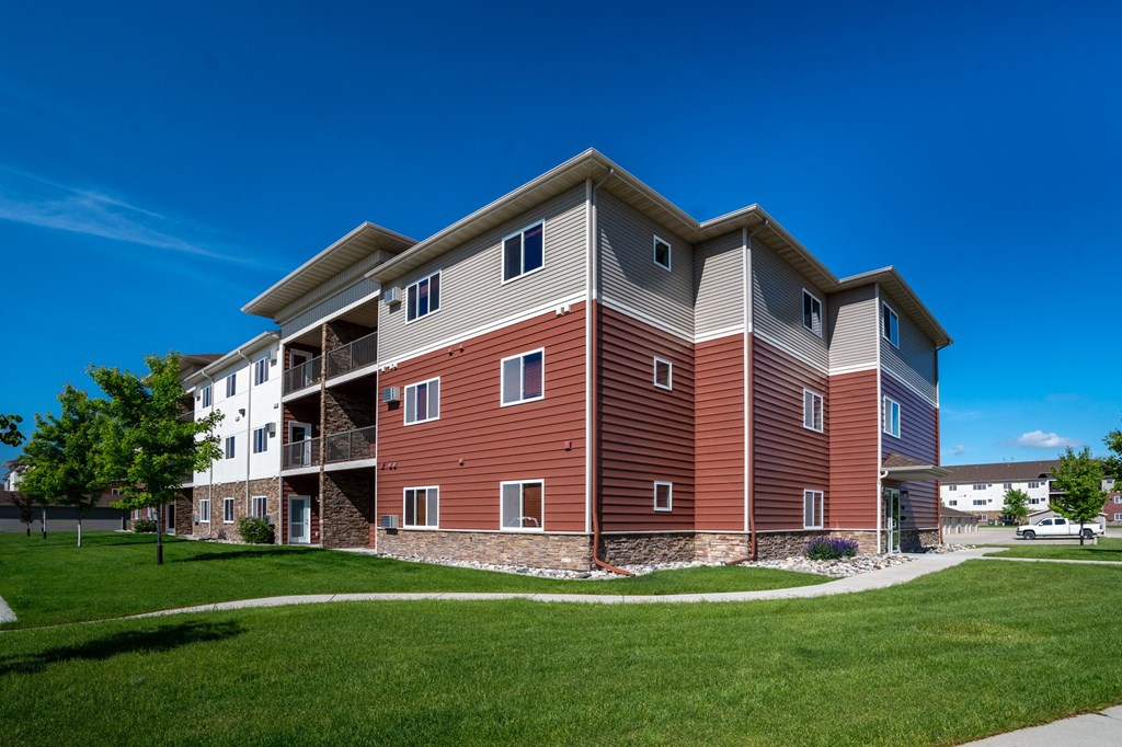 a modern apartment building with a green lawn and a blue sky
