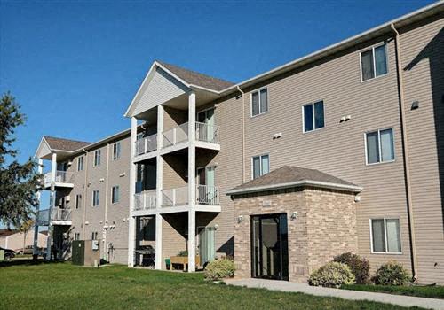 A large apartment building with a grassy area in front of it. Fargo, ND Eagle Run Apartments.