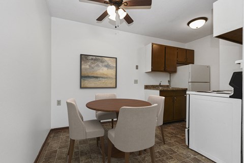 a dining area  in west st paul at Covington apartments with a table and 4 chairs and a kitchen in the background