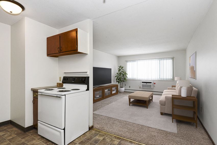 West St. Paul, MN Covington Courts Apartments | Living Room and Kitchen a living room in west st paul at Covington apartments. The room features modern furniture, including a comfortable sofa and chic coffee table. Soft lighting and tasteful decor contribute to a warm and inviting ambiance. Large windows allow natural light to illuminate the space, creating a bright and airy atmosphere.