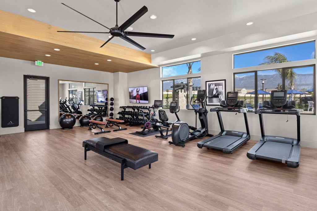 a gym with a lot of exercise equipment and windowsat Westbury Apartments, Rancho Cucamonga, California