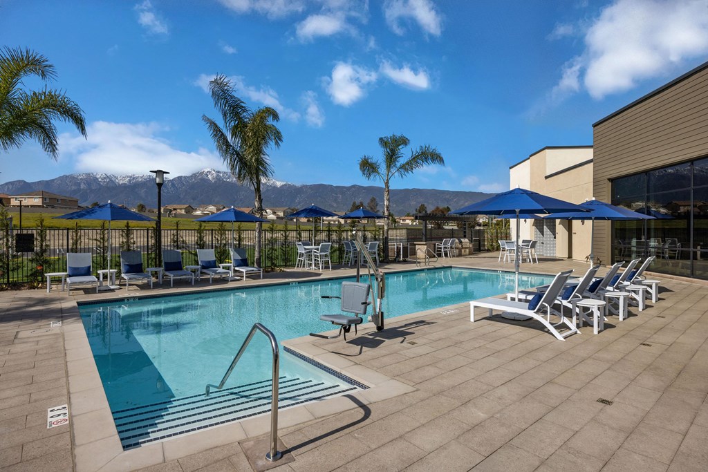 a swimming pool with chairs and umbrellas and mountains in the backgroundat Westbury Apartments, Rancho Cucamonga, California 