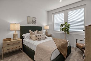 an empty bedroom with a bed and two windowsat Westbury Apartments, California, 91739