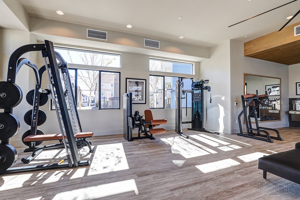 a gym with exercise equipment and windows at the district flats apartments  at Westbury Apartments, Rancho Cucamonga, California
