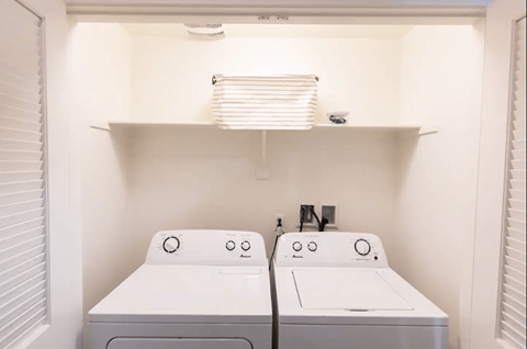 a white laundry room with two washers and a dryer
