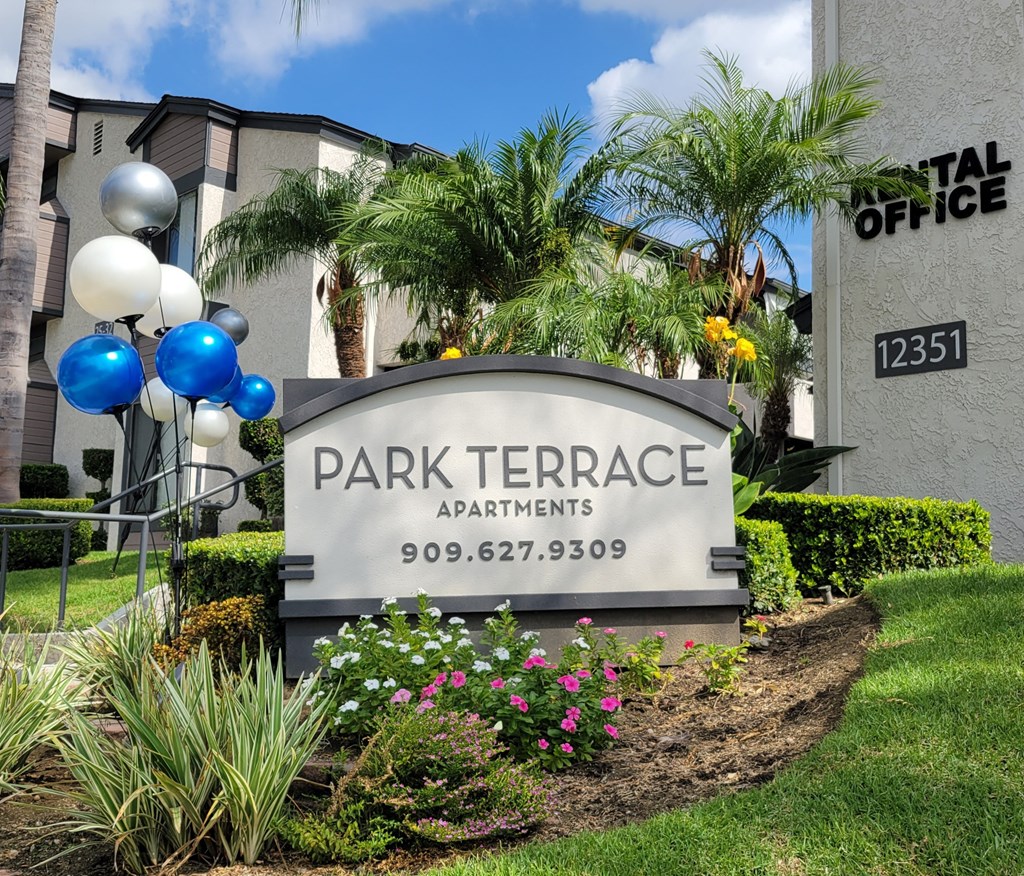 a sign for park terrace apartments in front of plants and flowers