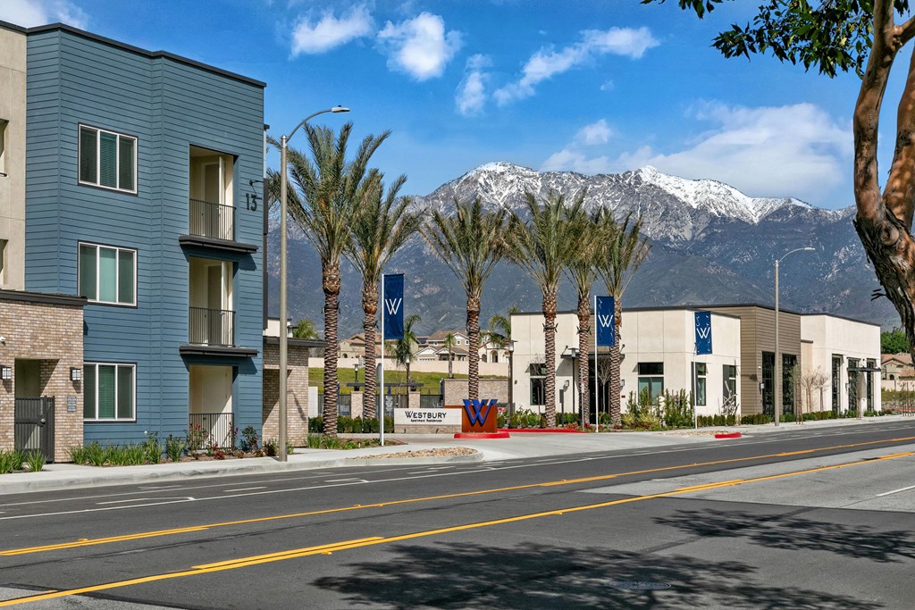 a city street with buildings and palm trees and mountains in the backgroundat Westbury Apartments, California, 91739