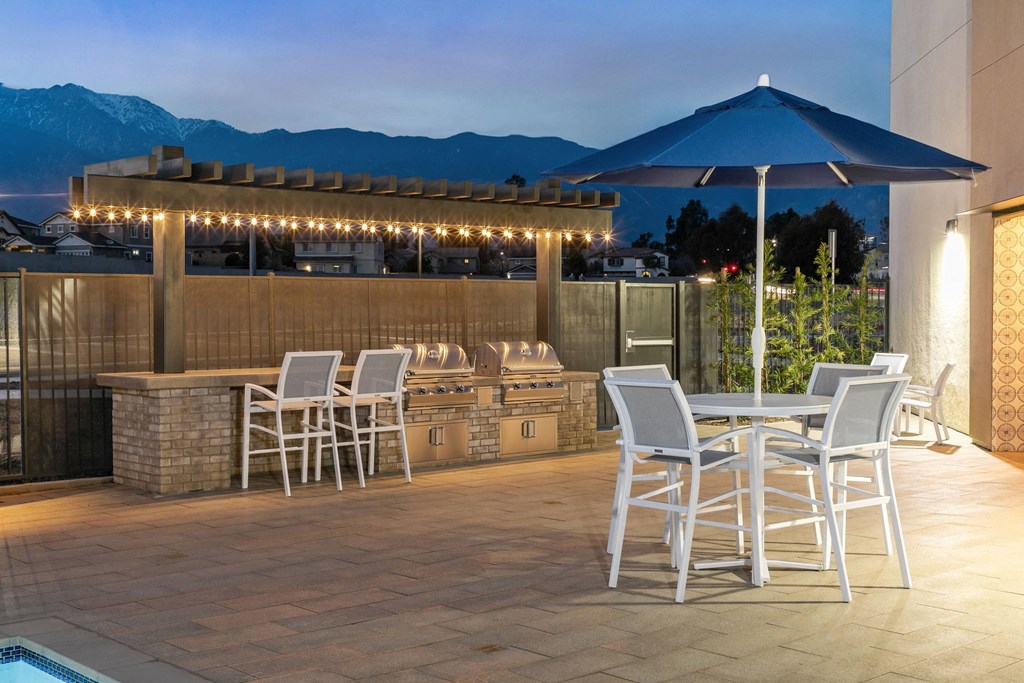 a patio with a bar and tables with chairs and umbrellasat Westbury Apartments, Rancho Cucamonga