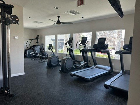 a gym with cardio equipment and windows in a building at Lincoln Park Apartments, Corona California