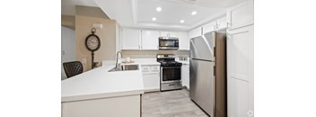A modern kitchen with a white countertop and stainless steel appliances. at The Oaks Apartments, California, 91786