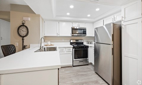 A modern kitchen with a white countertop and stainless steel appliances.