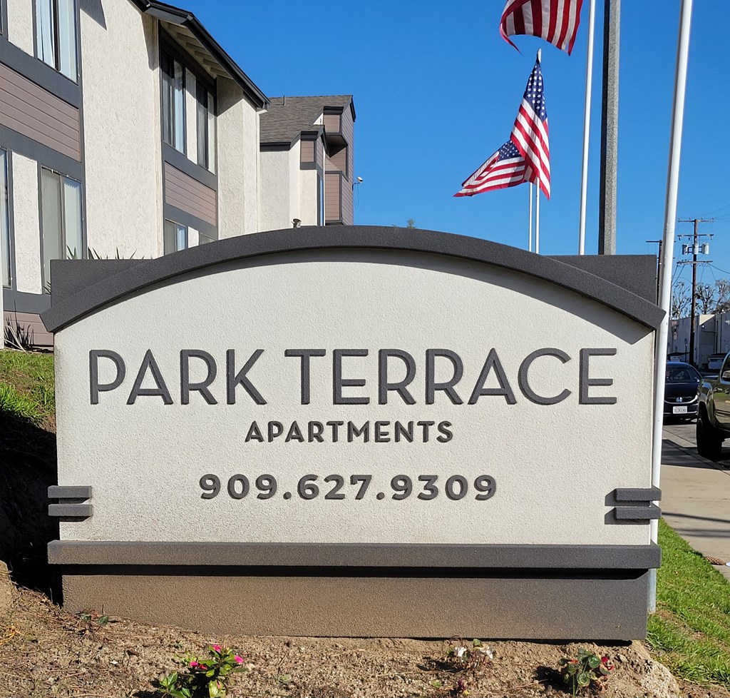a sign for park terrace apartments in front of two flags