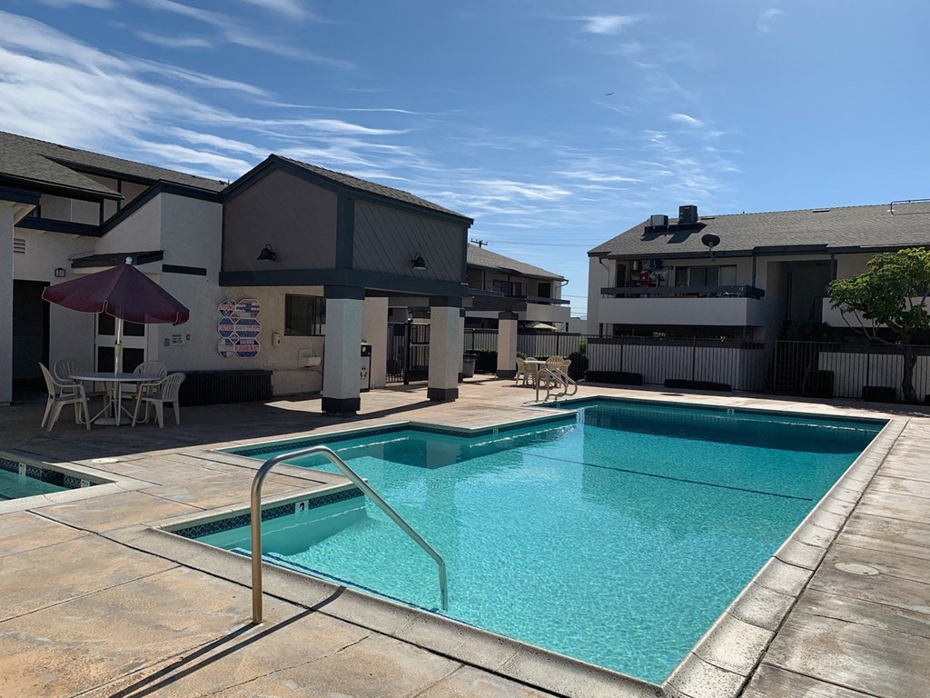 a swimming pool in front of a hotel with a blue sky