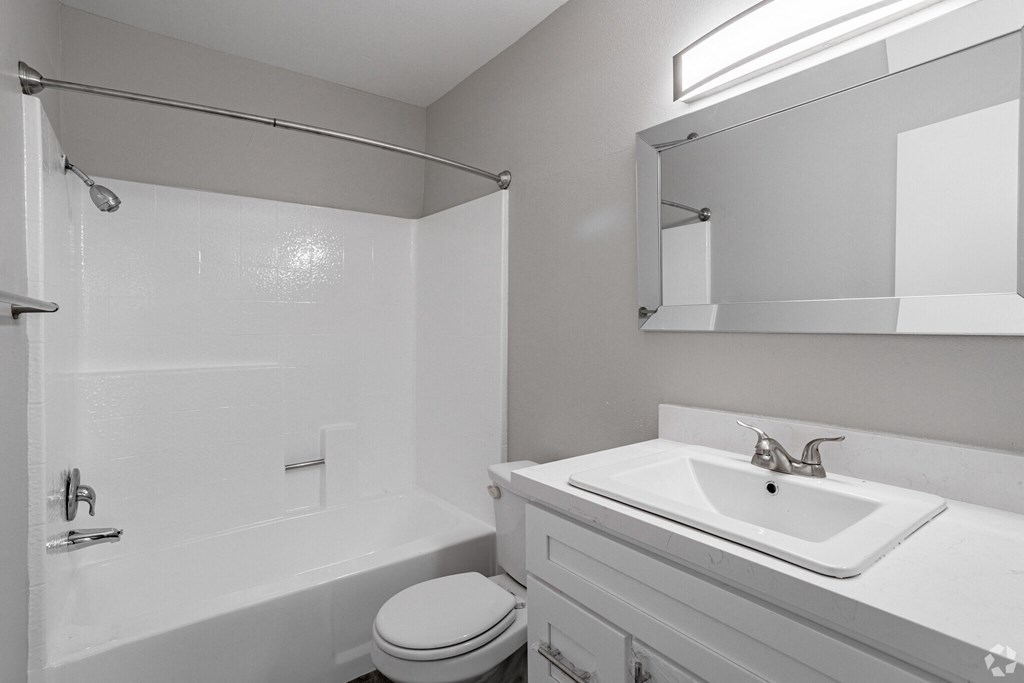A white bathroom with a toilet, sink, and shower.