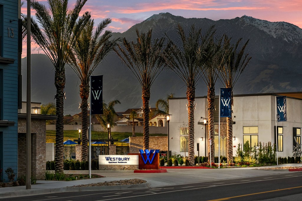 a city street with palm trees and a building with mountains in the backgroundat Westbury Apartments, Rancho Cucamonga, California 