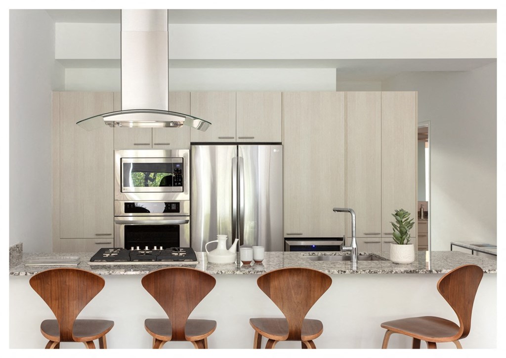 a kitchen with wooden chairs and a counter with a sink and a refrigerator