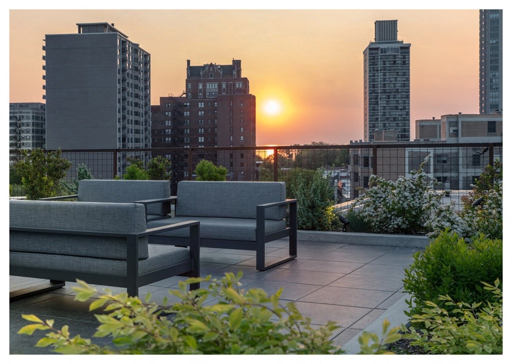 a view of the city from a rooftop terrace with chairs and a city skyline