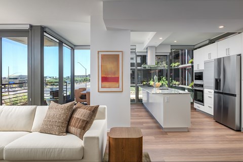 A modern kitchen with a white couch and a painting on the wall.