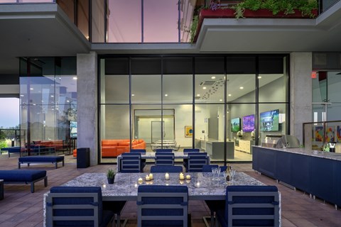 A modern outdoor dining area with a long table set for a meal.