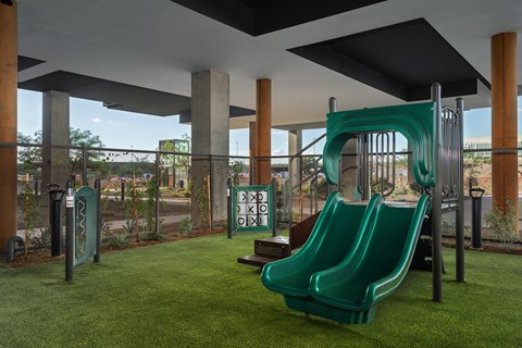 A playground with a green slide and a sign that says "KIDS".
