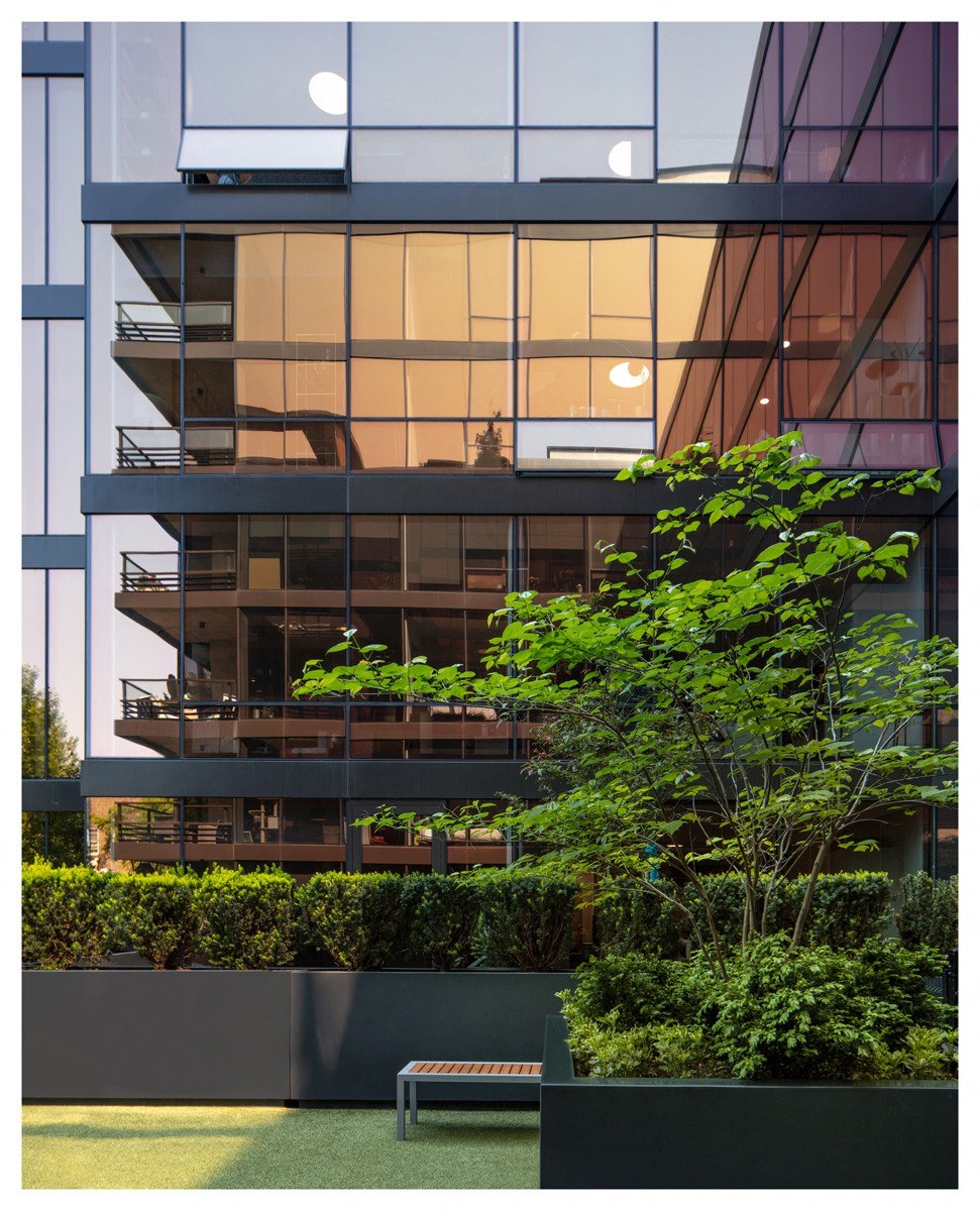 a view of the facade of an apartment building with trees and a bench