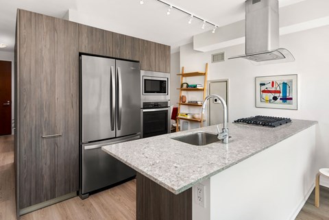 a kitchen with a marble counter top and a stainless steel refrigerator
