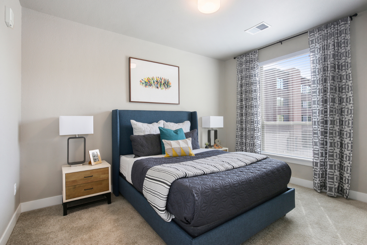 A bedroom with a large bed and a window with curtains.