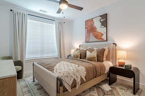 A bedroom with a large bed and a ceiling fan.