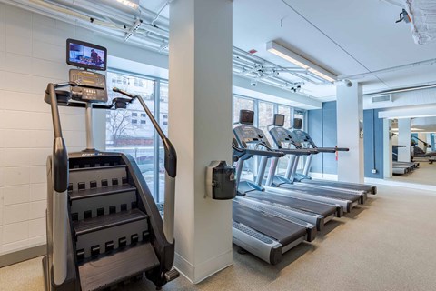 A gym with treadmills and a television on the wall.