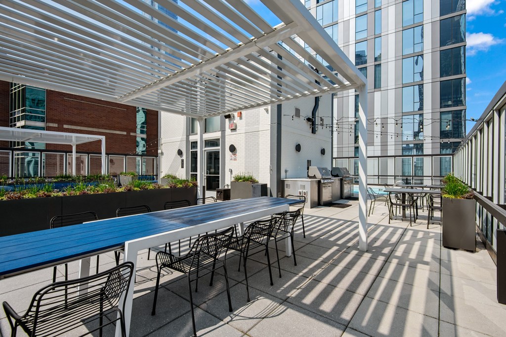 A patio with tables and chairs is covered by a white roof.