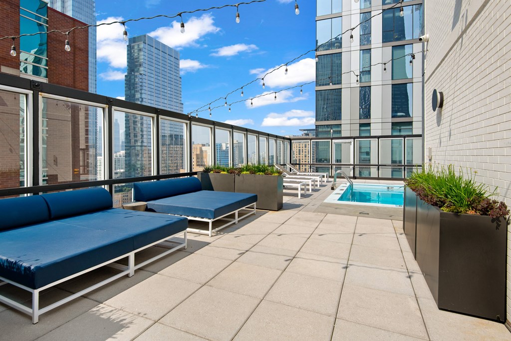 A rooftop patio with a pool and lounging area.