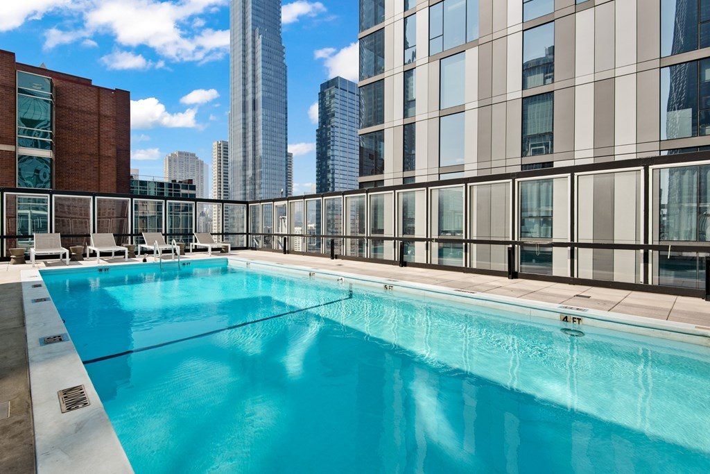 A large swimming pool on a rooftop with a city skyline in the background.