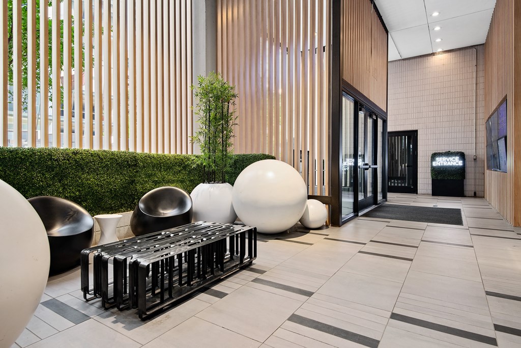 A modern lobby with a green hedge and a black and white bench.