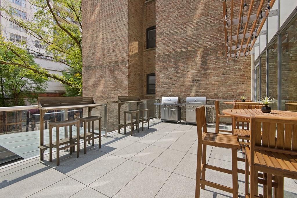 a patio with tables and chairs and a brick wall
