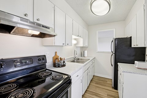 A kitchen with a black stove top oven and white cabinets.
