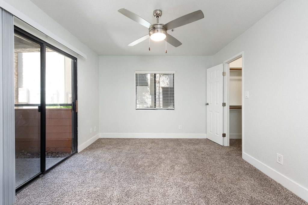 an empty living room with a ceiling fan and a glass door