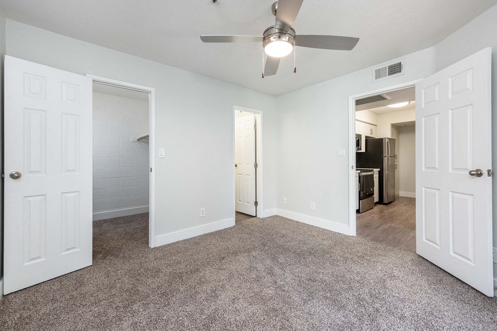 an empty living room with white doors and a ceiling fan