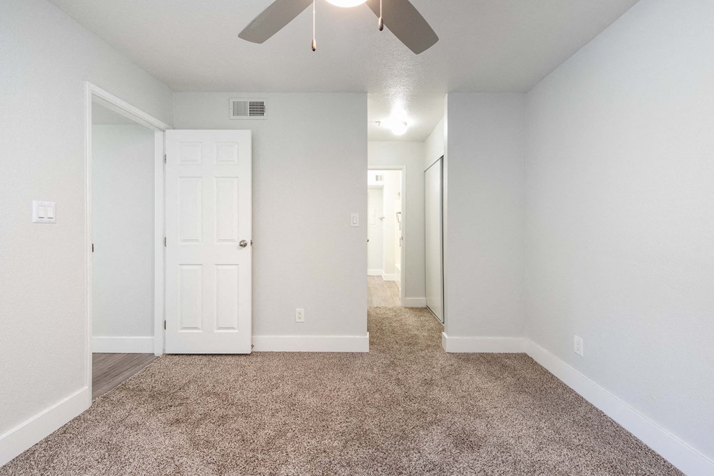 an empty room with carpet and a ceiling fan