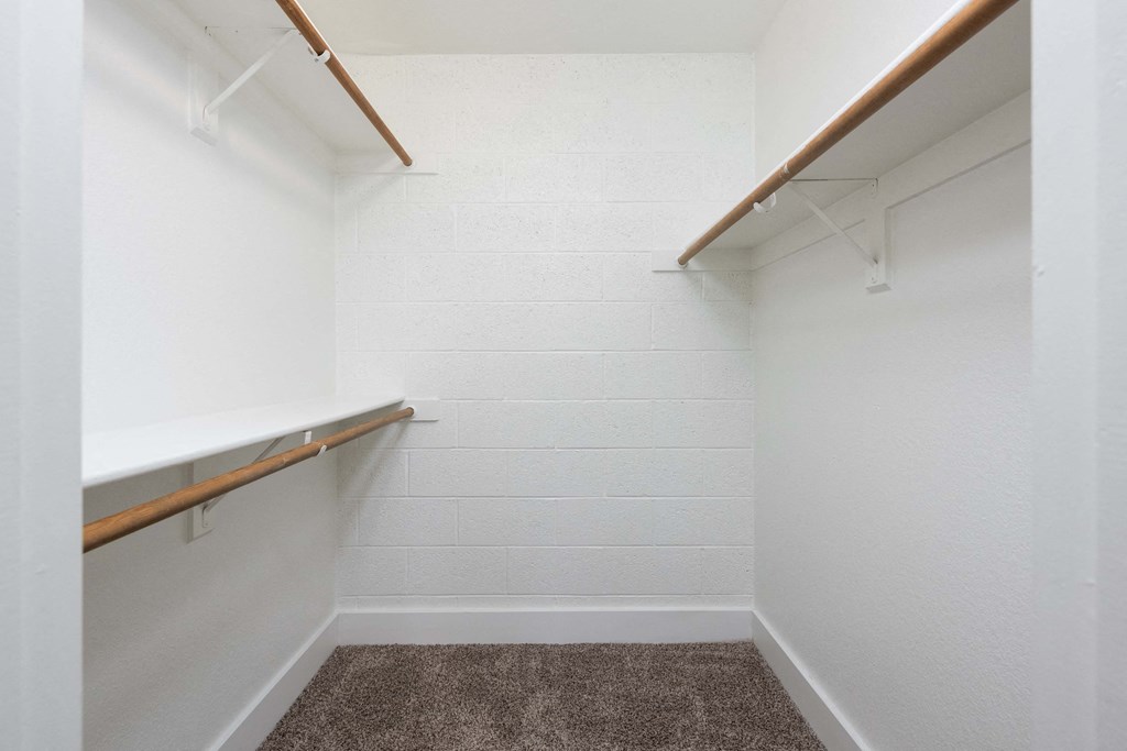 a walk in closet in a white room with white walls and a carpet