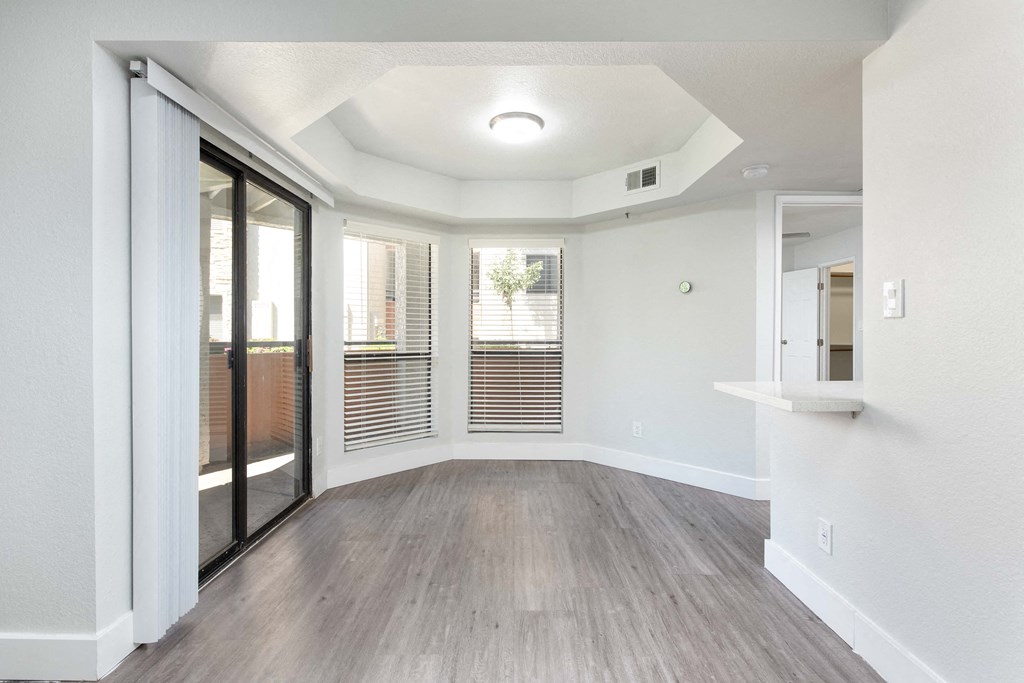 the living room of an apartment with wood flooring and sliding glass doors