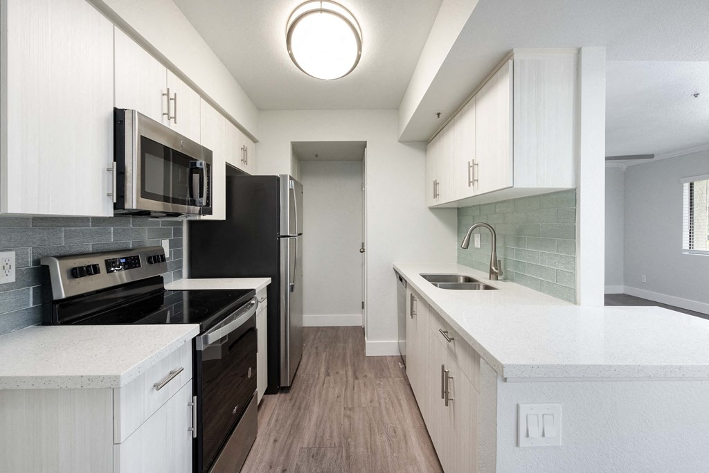 an empty kitchen with white cabinets and a black stove and refrigerator
