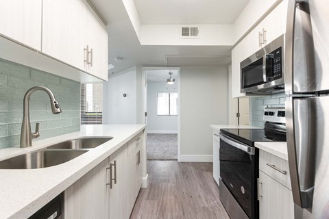 a kitchen with white cabinets and a sink and a refrigerator