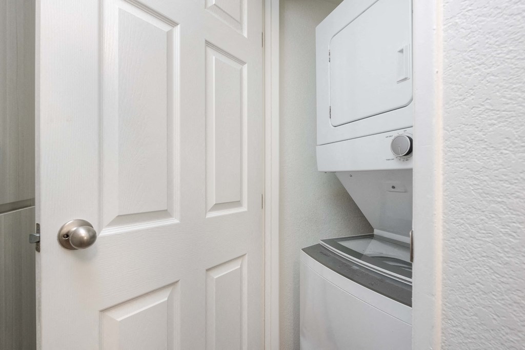 an open door to a laundry room with a dryer on the wall