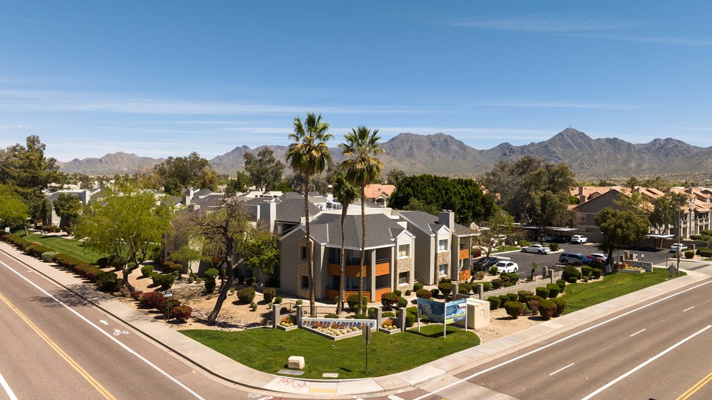 an aerial view of a building with palm trees and a street