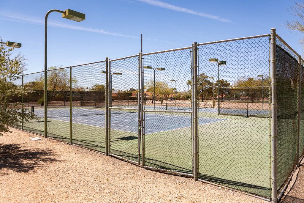 a tennis court with a chain link fence and a lamp post