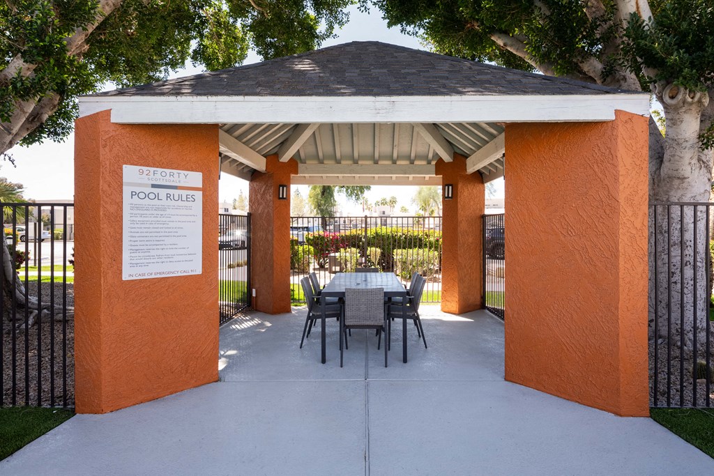 a patio with a table and chairs under a gazebo